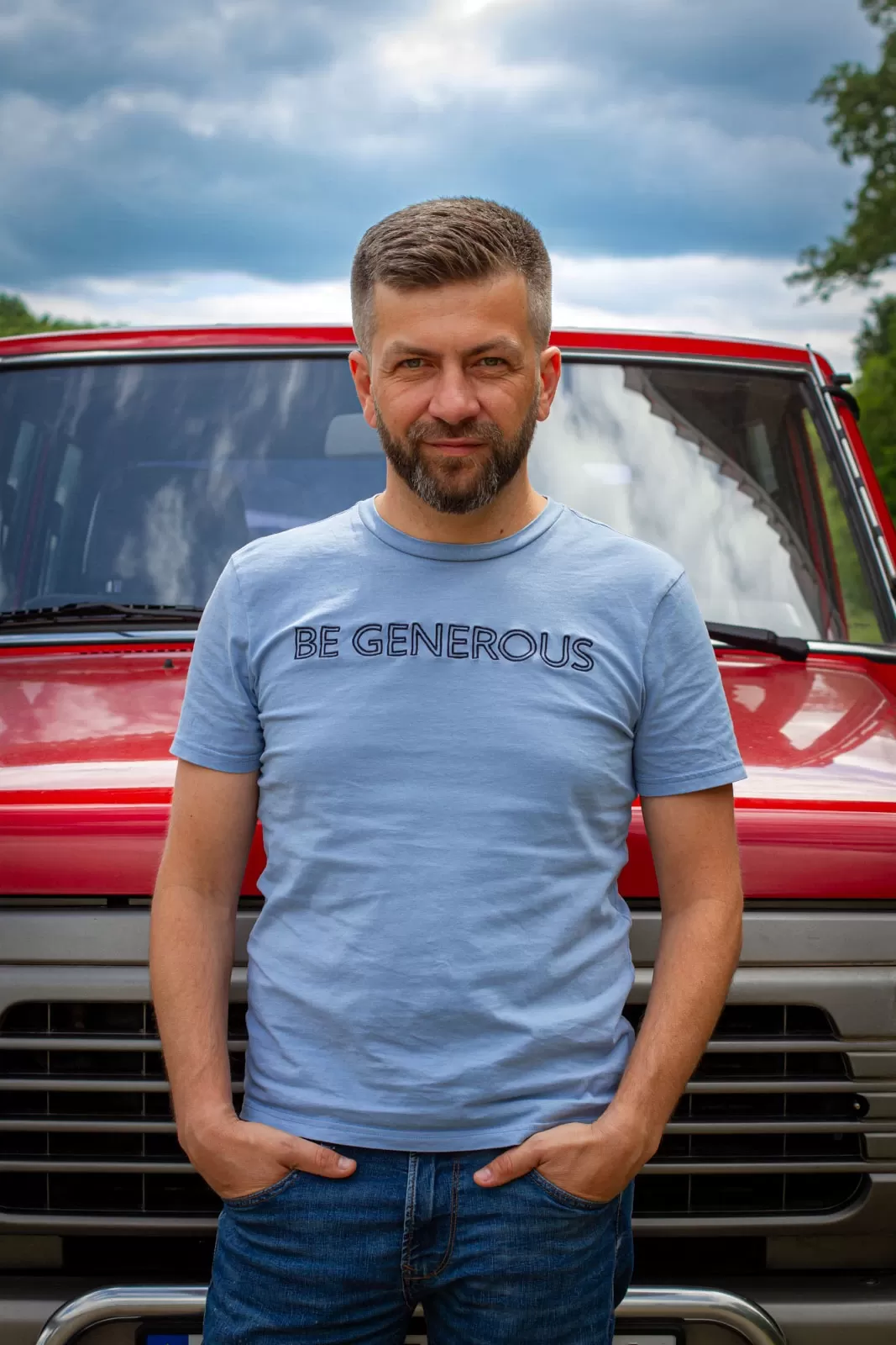 Marcin Maciejewski - mężczyzna na tle czerwonego samochodu